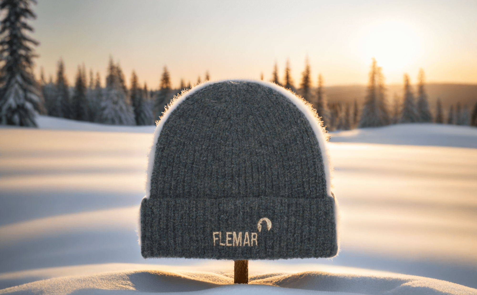 Bonnet Flemar en laine d'alpaga posé sur la neige avec un coucher de soleil